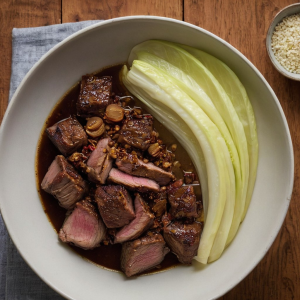 Braised lamb cubes seasoned with cumin and Szechuan peppercorns served alongside wilted Napa cabbage.